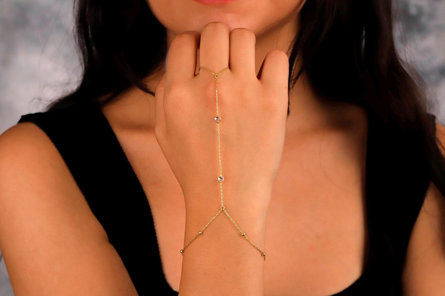 Woman wearing a gold arm chain against a neutral background