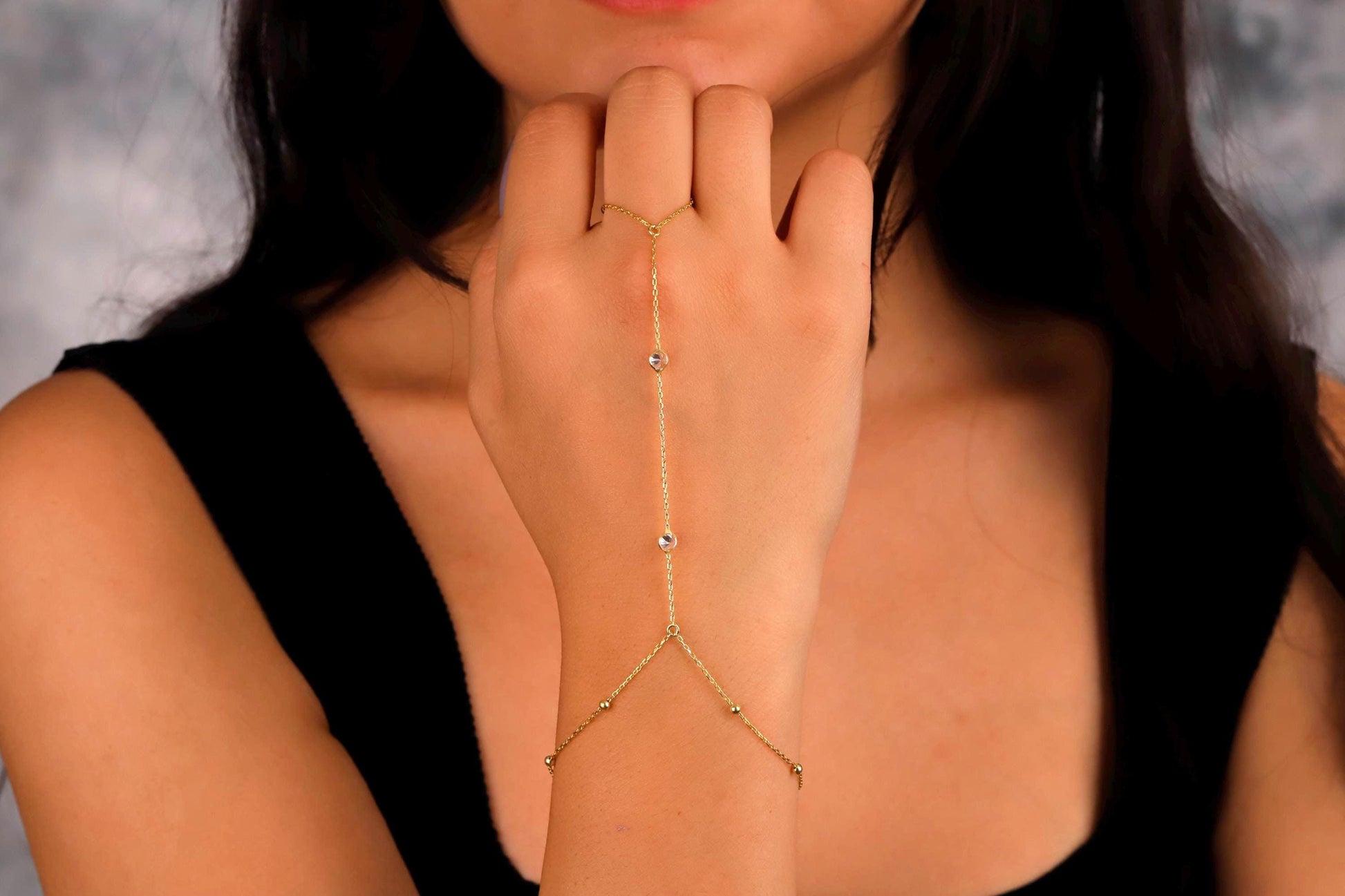 Woman wearing a gold arm chain against a neutral background