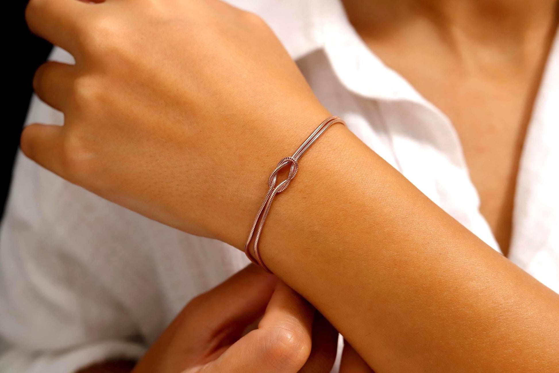 Close-up of a person wearing a silver bracelet on a white background