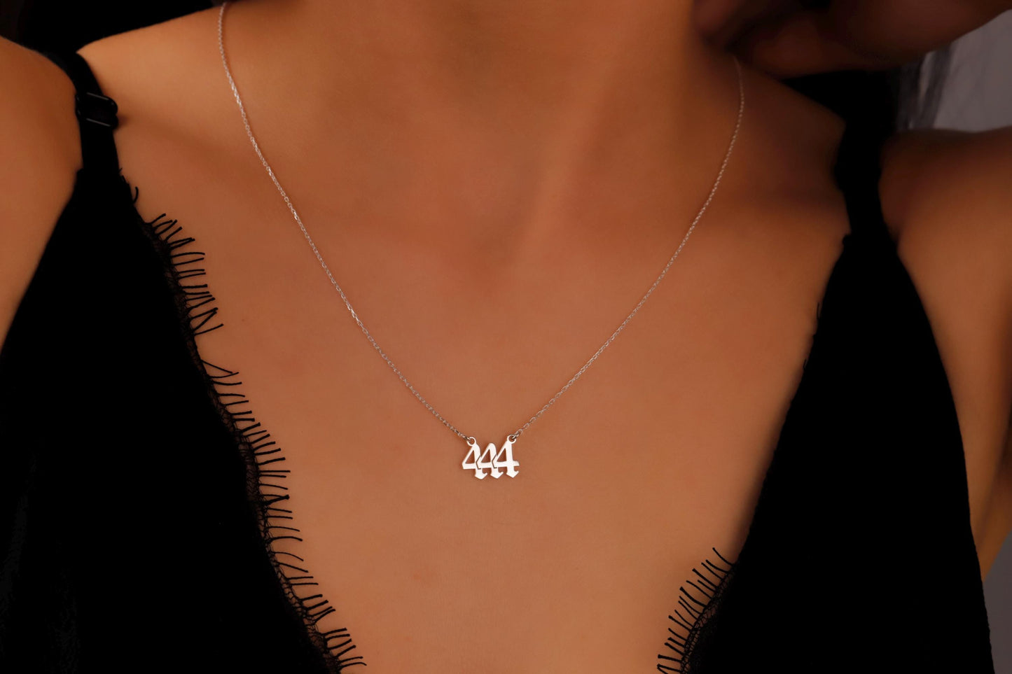 Silver necklace with a pendant on a person wearing a black top.