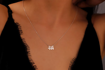 Silver necklace with a pendant on a person wearing a black top.
