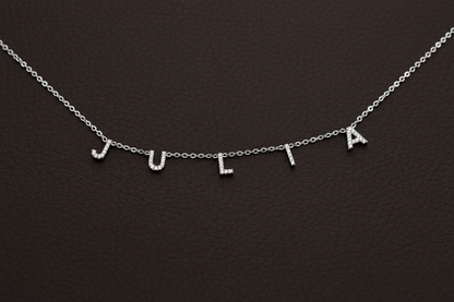 Silver necklace with 'JULIA' letters on a dark background