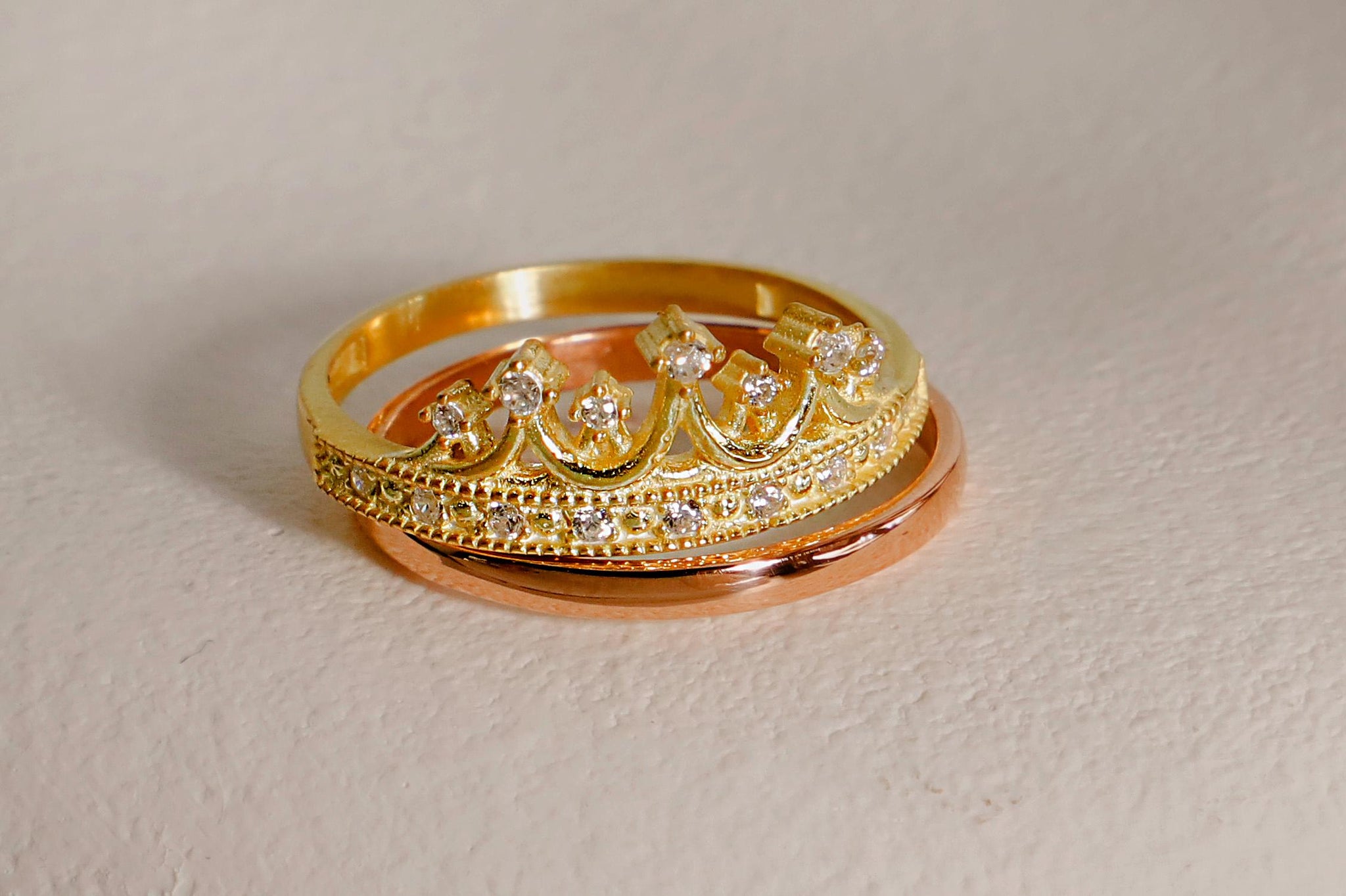 Two gold rings with diamond accents on a white background
