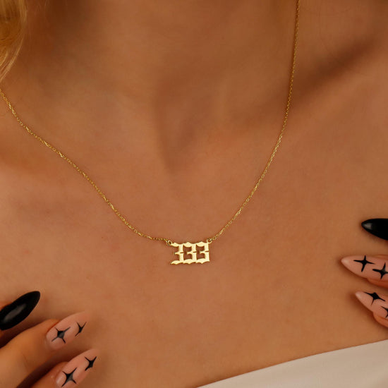 A close-up video of a necklace with the number '444 on a charm, held by a person with red nail polish.