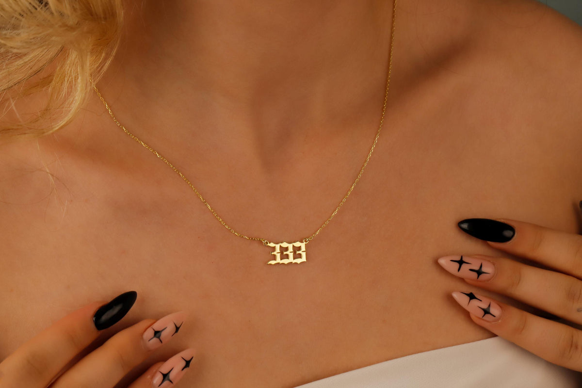 A close-up video of a necklace with the number '444 on a charm, held by a person with red nail polish.