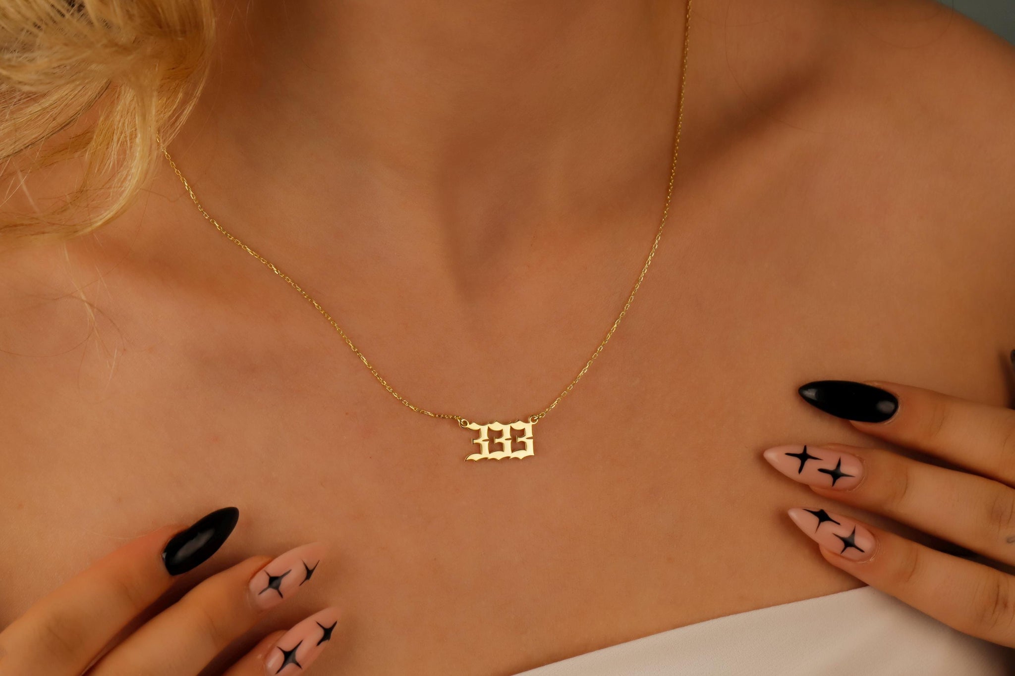 A close-up video of a necklace with the number '444 on a charm, held by a person with red nail polish.