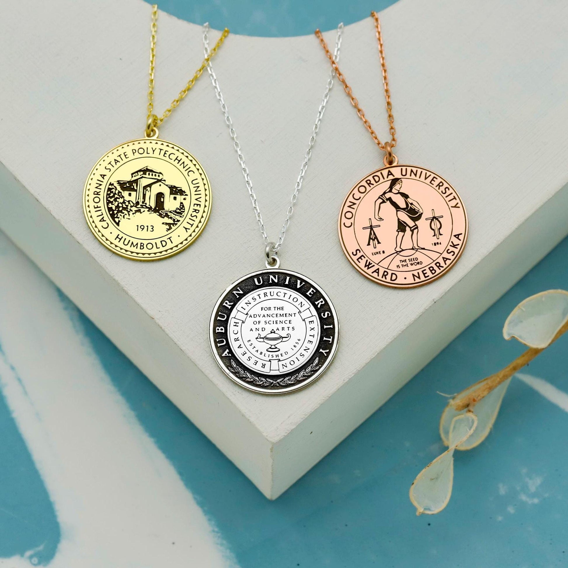 Gold necklace with a pendant worn by a person with black nail polish.
