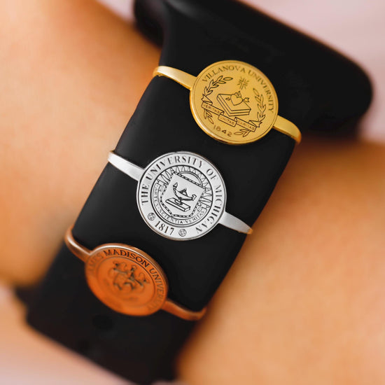 Black smartwatch with a gold emblem on a wrist against a neutral background
