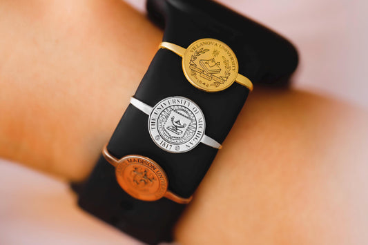 Black smartwatch with a gold emblem on a wrist against a neutral background