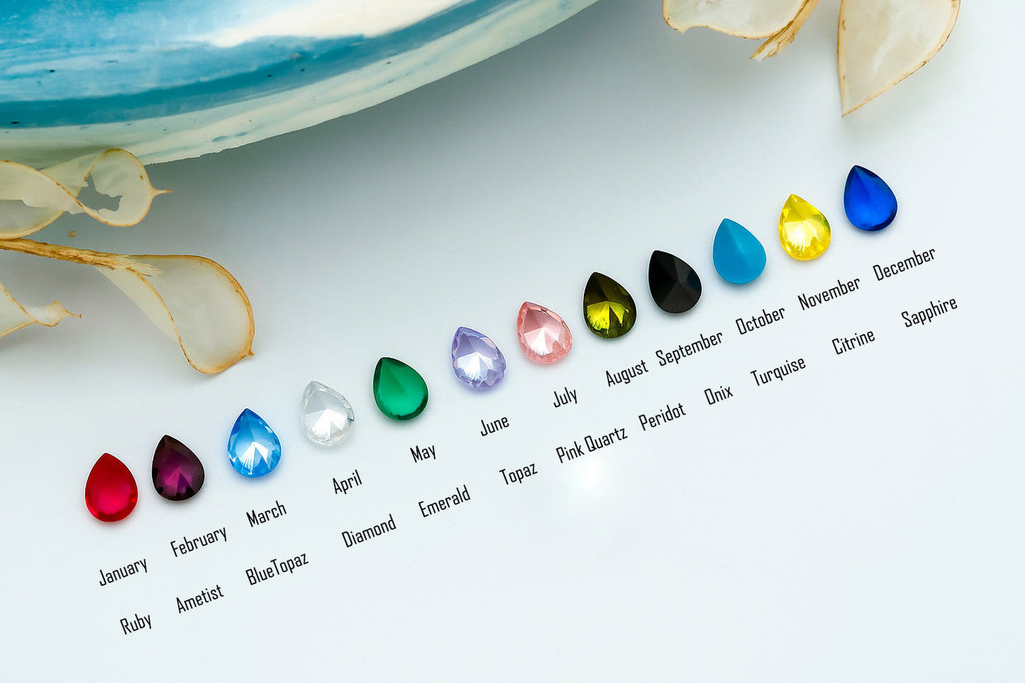 Set of colorful gemstones corresponding to each month on a light surface.